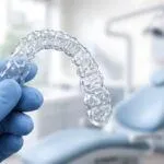 Clear Dental Aligner Held by Gloved Hand in Modern Dental Office